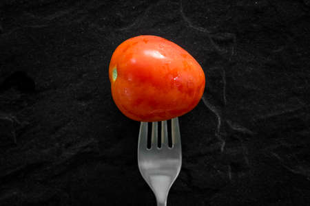 Tomato with fork on black backgroundの写真素材