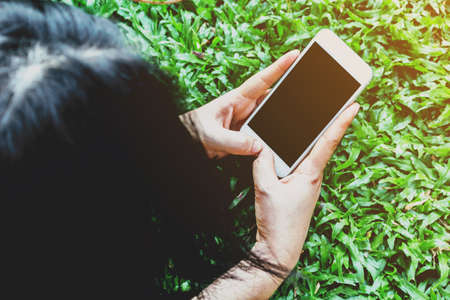  Young woman touching smartphone on green grassの写真素材