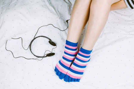 Woman leg and earphone on white bed