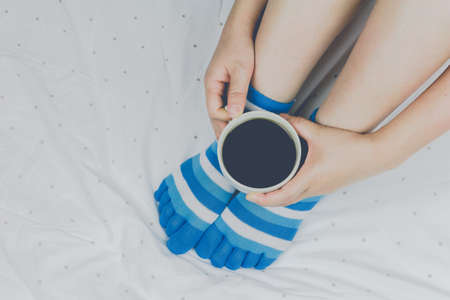 Woman holding cup of coffee on the bedの写真素材
