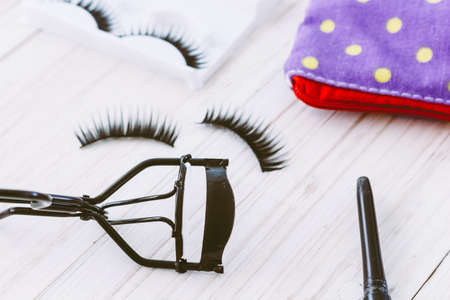 Curler and false eyelashes on wooden backgroundの写真素材