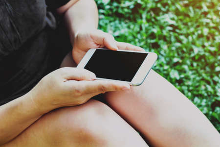  Young woman touching smartphone on green grassの写真素材