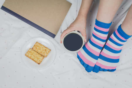 Woman holding cup of coffee on the bed