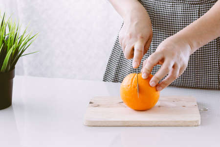 Girl cutting orange with the knifeの写真素材