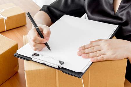Woman signs clipboard for deliveryの写真素材