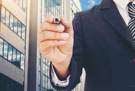Businessman writing on copy space on Office buildings backgroundの写真素材