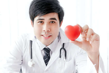 Asian doctor with stethoscope holding red heart - medical and health conceptの写真素材