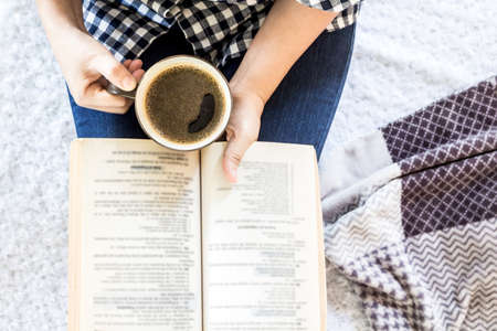 Woman with cup of coffee reading a bookの写真素材