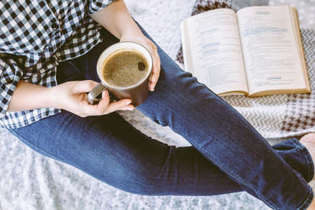 Woman with cup of coffee reading a bookの写真素材