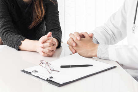 Doctor and woman patient consulting on doctors table