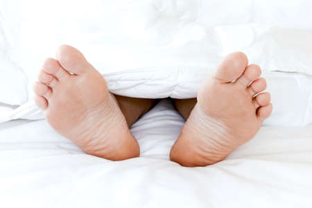Young woman's bare feet on white blanketの写真素材