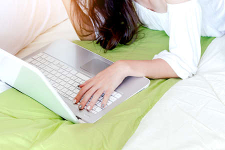 Woman using laptop computer on bed at home