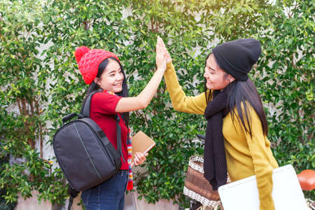 Woman student waving and clapping their hands with her friend - friendship and togetherness conceptの写真素材