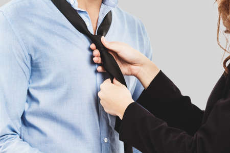 Woman adjusting tie of businessman on gray backgroundの写真素材