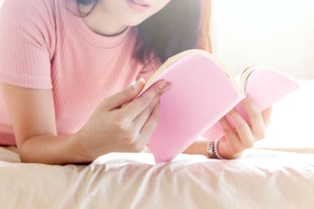 Woman reading book on bed in the morningの写真素材
