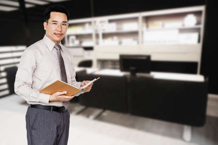 Businessman holding a book on office blur background