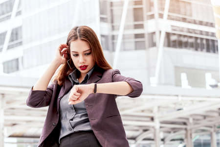 Business woman looking at watch at office buildingの写真素材