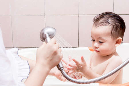 Mother washing shower with baby in bathの写真素材