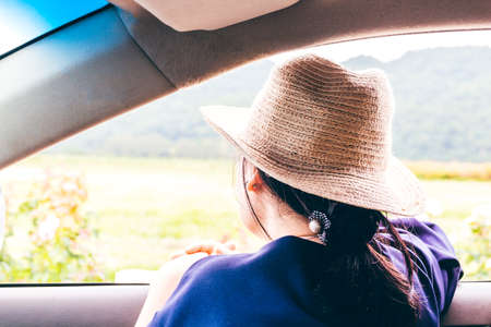 Woman relaxing out of window in car with mountain backgroundの写真素材