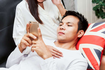 Young couple relaxing with smartphone on the sofa couchの写真素材