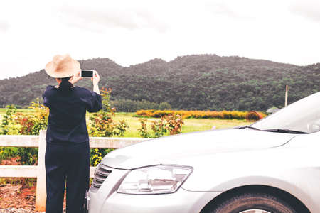 Woman relaxing with car and mountain backgroundの写真素材