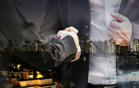 Handshake of business partners on city background - Double exposure photoの写真素材