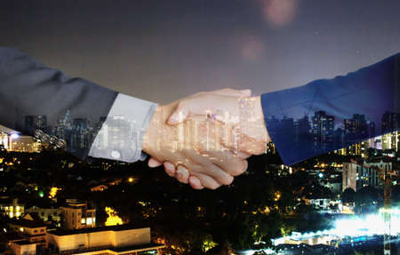Handshake of business partners on city background - Double exposure photoの写真素材