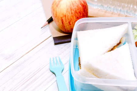 Lunch box with vegetables and slice of bread for a healthy school lunch on wooden tableの写真素材