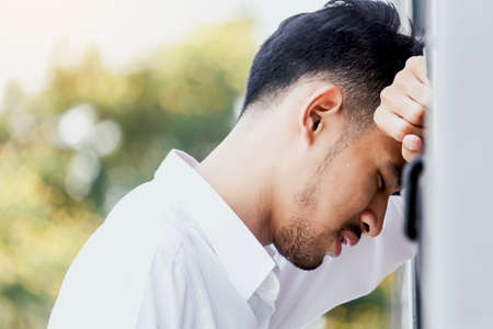 Sad man standing near a wallの写真素材