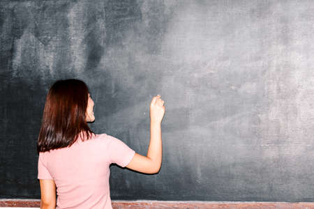 Young college student writing on blackboardi in classの写真素材