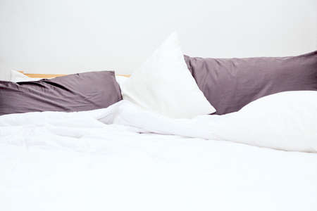 Messy bed and white bedding sheets and pillowの写真素材
