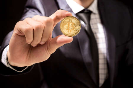 Businessman holding bitcoin on black backgroundの写真素材
