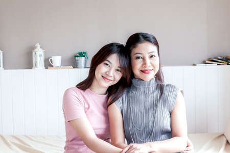Mother and teenage daughter smiling at homeの写真素材