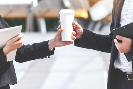 Business people holding a paper coffee cupの写真素材