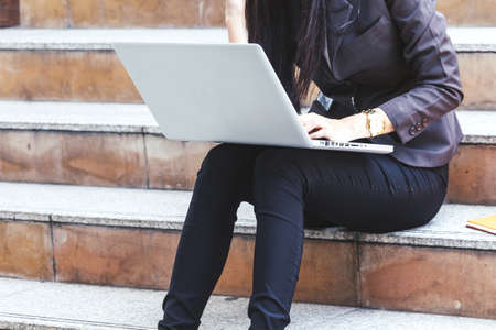 Business woman sitting on stairs and using laptopの写真素材