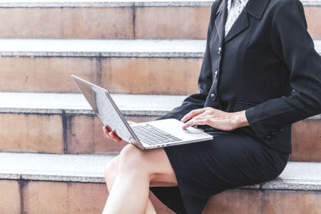 Business woman sitting on stairs and using laptopの写真素材