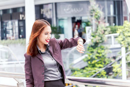 Business woman looking at watch at office buildingの写真素材