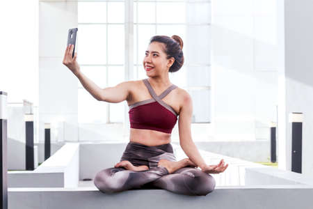 Woman practicing yoga and use tablet in the parkの写真素材