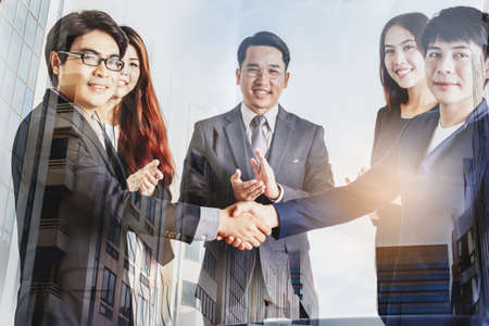 Handshake of business partners on blur office building background - Double exposure photoの写真素材