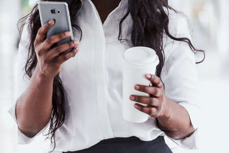 African american woman with coffee and smartphoneの写真素材
