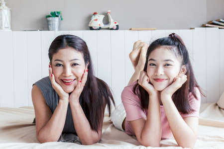 Mother and teenage daughter smiling at homeの写真素材