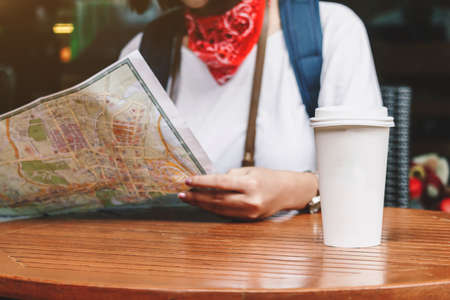 Woman tourist travel holding map with cup of coffee in coffee shop