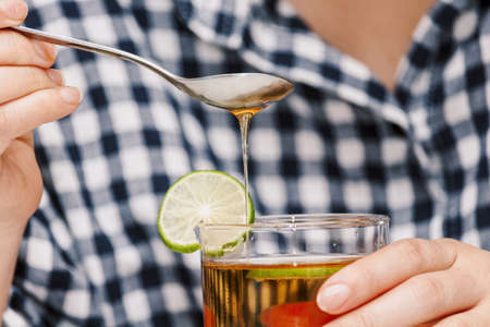 Woman hand add honey into lemon teaの写真素材
