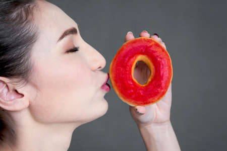 Woman holding donut on gray backgroundの写真素材