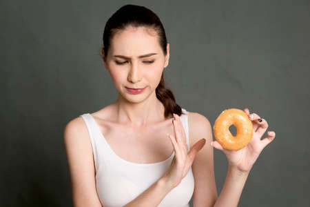 Woman holding calorie bomb donut on gray background. Junk food conceptの写真素材