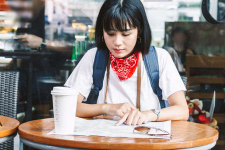 Woman tourist travel holding map with cup of coffee in coffee shopの写真素材