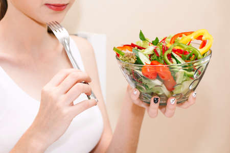 Woman holding fresh vegetable salad in glass bowl. Woman diet conceptの写真素材