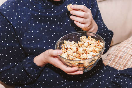 Woman eating popcorn on sofaの写真素材