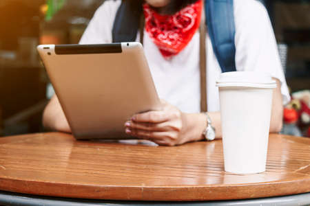 Woman using tablet and cup of coffee in coffee shop