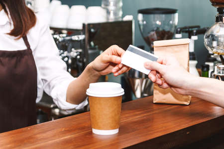 Female barista  taking a credit card from customer in coffee shopの写真素材